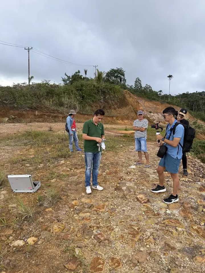 A team on a hillside mining site while one person measures with equipment.