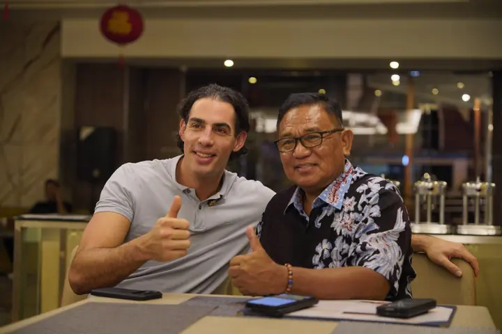 Two men at a table smiling and giving a thumbs up.