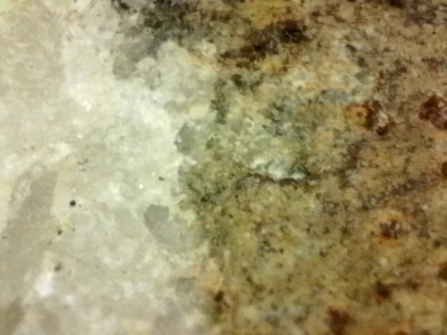 Close-up microscope picture of ore: a rust-brown mineral spot in white and grey quartz.